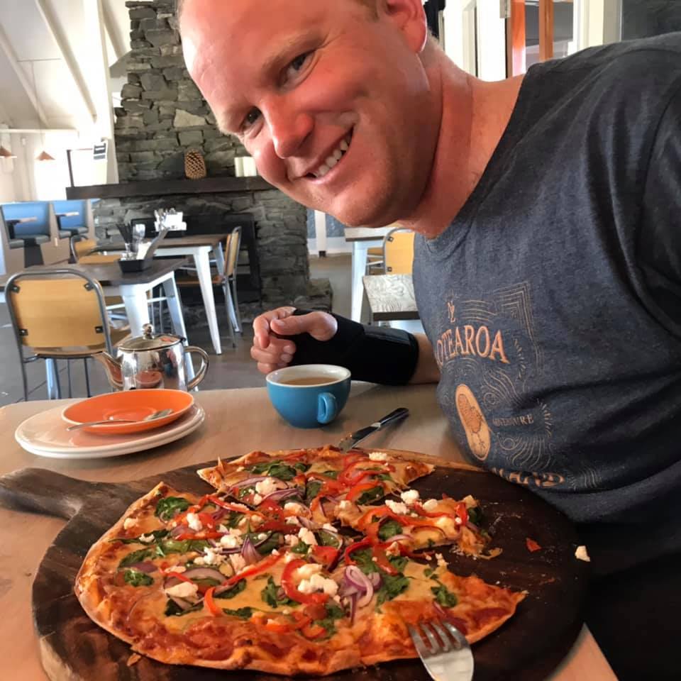 Rob Hutchings eating a pizza after swimming the Clutha River